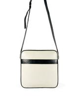 Square medium cross body bag. Cream colored leather with black leather accent stripe on front panel and black piping. Lightweight black cotton lining. Silver buckle on adjustable black leather cross body strap. Slip pocket on back panel. Upcycled, circular, sustainable. Front view.