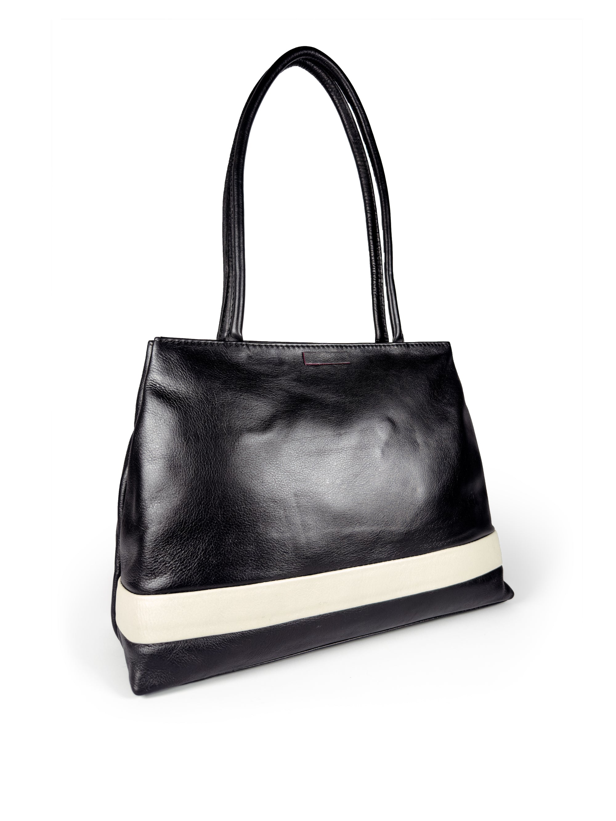 Black leather medium sized handbag, with tapered top. Inlaid white leather accent stripe on front panel. Magnet depth expansion. Chic padded pipe shoulder straps. Upcycled, circular, sustainable. 3/4 view 1.