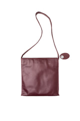 Large slim cross body bag in polished classic burgundy brown leather. Deep grapefruit pink satin lining and stitch accents. Chic wide strap. Magnet closure. Front view. Upcycled, circualr, sustainable.