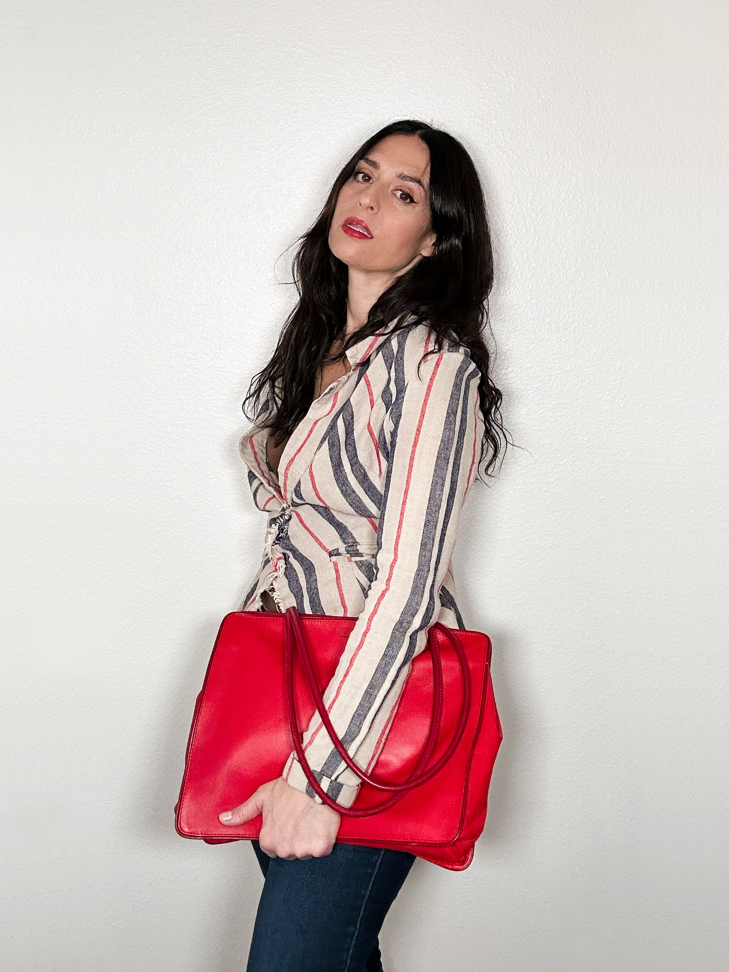 Woman holding a red handbag against a plain background