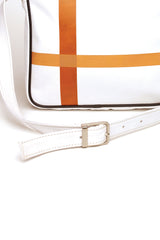 Square medium cross body bag, white coil zip closure, all white lightly distressed leather with two toned orange silkscreen off-center cross, black piping. Silver buckle on adjustable cross body strap. Upcycled, circular, sustainable. Detail view.