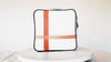 Square medium cross body bag, white coil zip closure, all white lightly distressed leather with two toned orange silkscreen off-center cross, black piping. Silver buckle on adjustable cross body strap. Upcycled, circular, sustainable. 360 view.