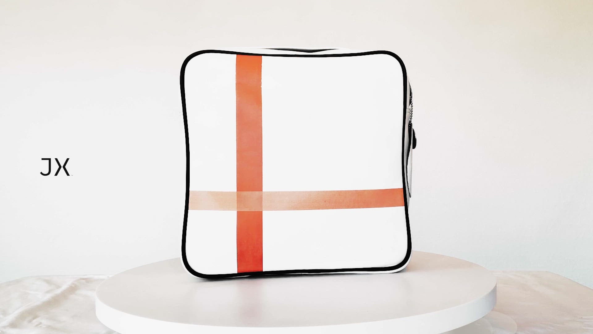 360 product video. Square medium cross body bag, white coil zip closure, all white lightly distressed leather with two toned orange silkscreen off-center cross, black piping. Silver buckle on adjustable cross body strap.