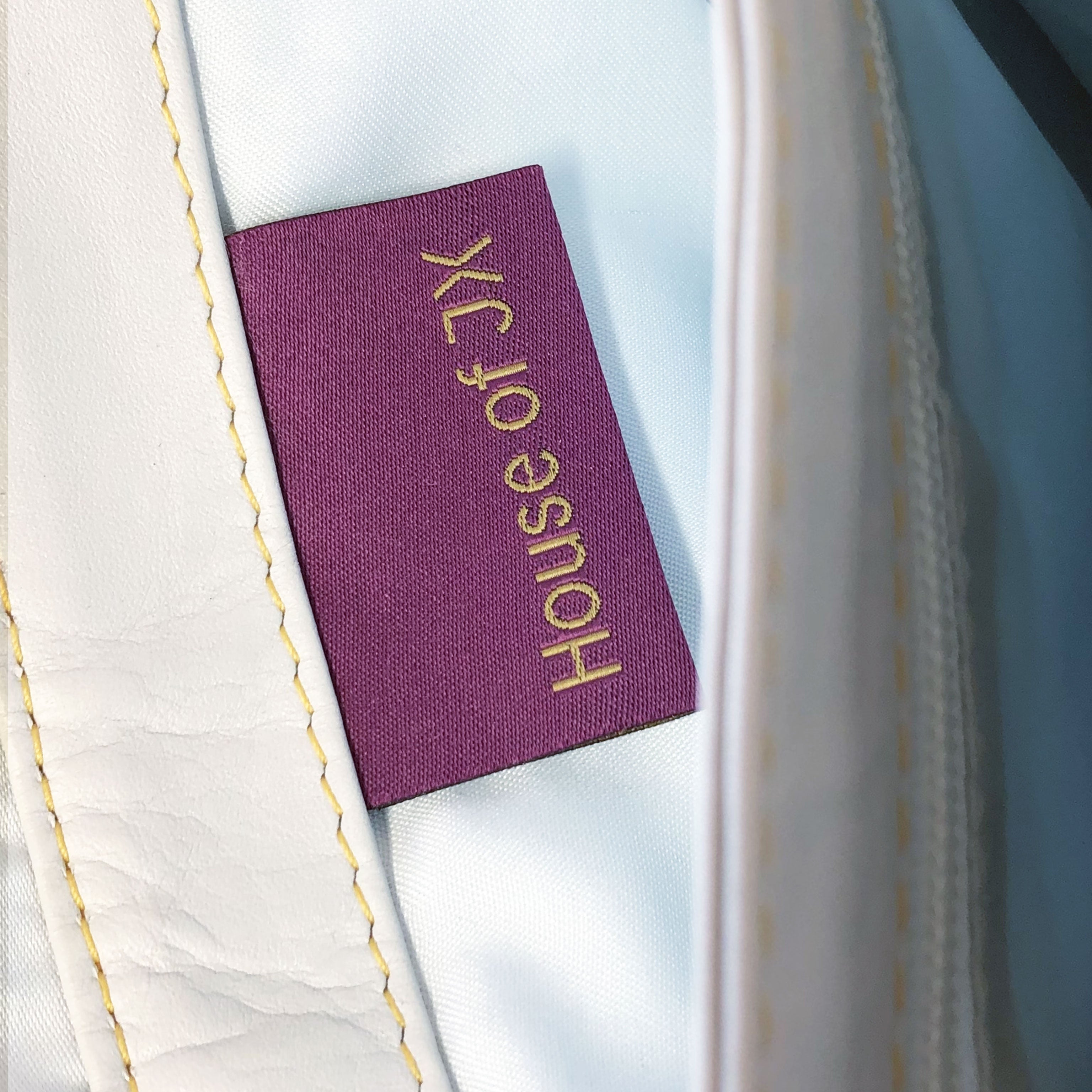 House of JX - White & dark grey leather small messenger bag. White lining, yellow stitches. Padded cross body strap. Plum & gold woven label detail. Upcycled, sustainable